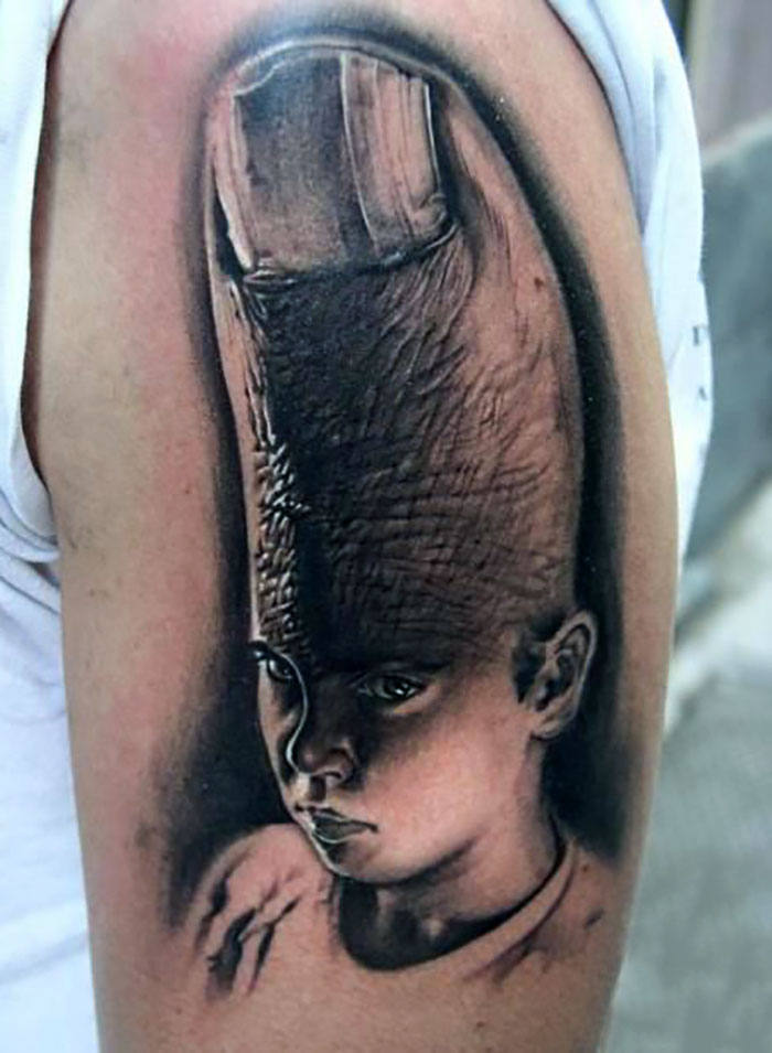 Tatuaje en brazo con diseño surrealista de niño con dedo gigante en la cabeza, ejemplo de tatuajes horribles.