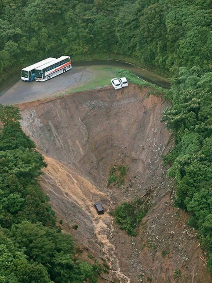 Cráter gigantesco en área boscosa con vehículos al borde, uno dentro, mostrando lugares misteriosos en Google Earth.