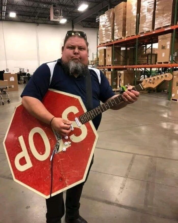 Hombre con guitarra hecha con señal de alto al revés en bodega, imagen maldita y curiosa a todos los niveles.