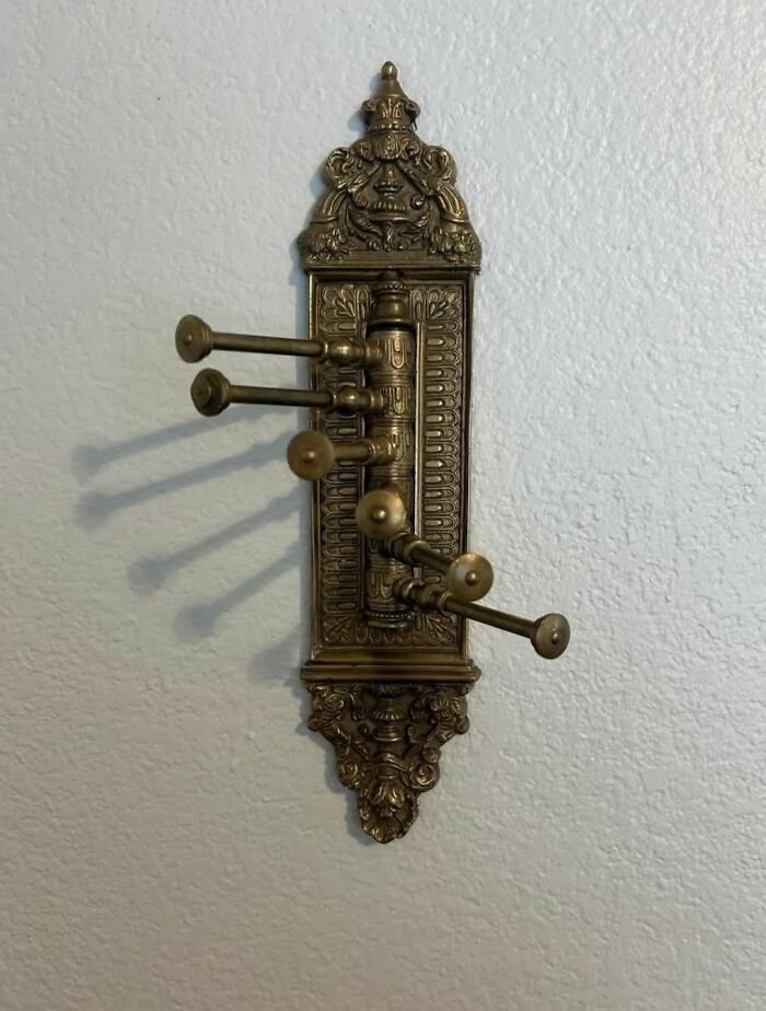 Gancho de bronce antiguo con detalles ornamentales en casa olvidada, mostrando descubrimientos curiosos en casas abandonadas.