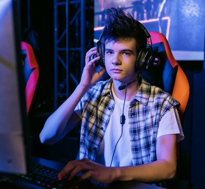Joven usando auriculares y teclado en un entorno de juego, aplicando trucos vitales muy útiles en el día a día.