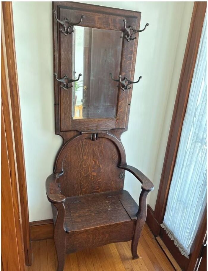 Silla recibidor antigua con espejo y ganchos de madera en casa olvidada con descubrimientos curiosos y objetos antiguos.