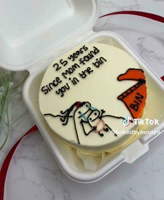 Pastel con dibujo y texto humorístico mostrando una imagen bendecida y maldita al mismo tiempo en caja para llevar.