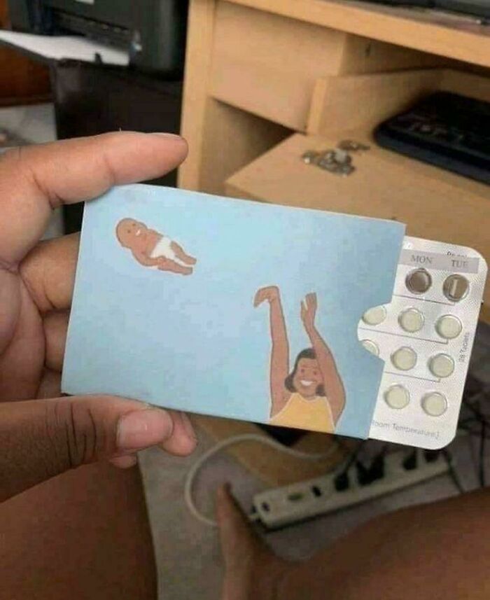Mano sosteniendo pastillas anticonceptivas con dibujo de persona lanzando bebé, imagen bendecida y maldita.