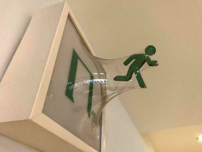 Figura verde saliendo de una señal de salida en una imagen creativa que parece bendecida y maldita al mismo tiempo