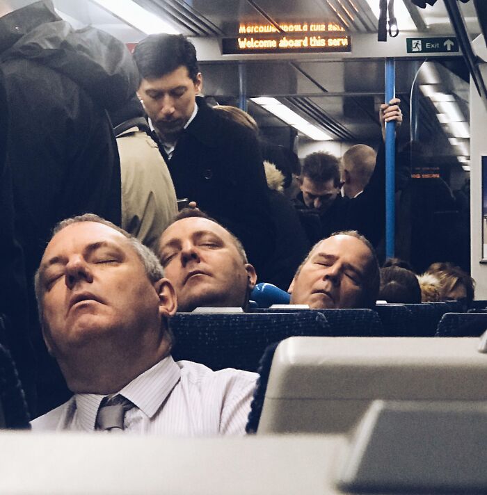 Tres hombres dormidos en asiento del tren, coincidencia increíble de expresiones y postura casi idénticas en espacio reducido público.