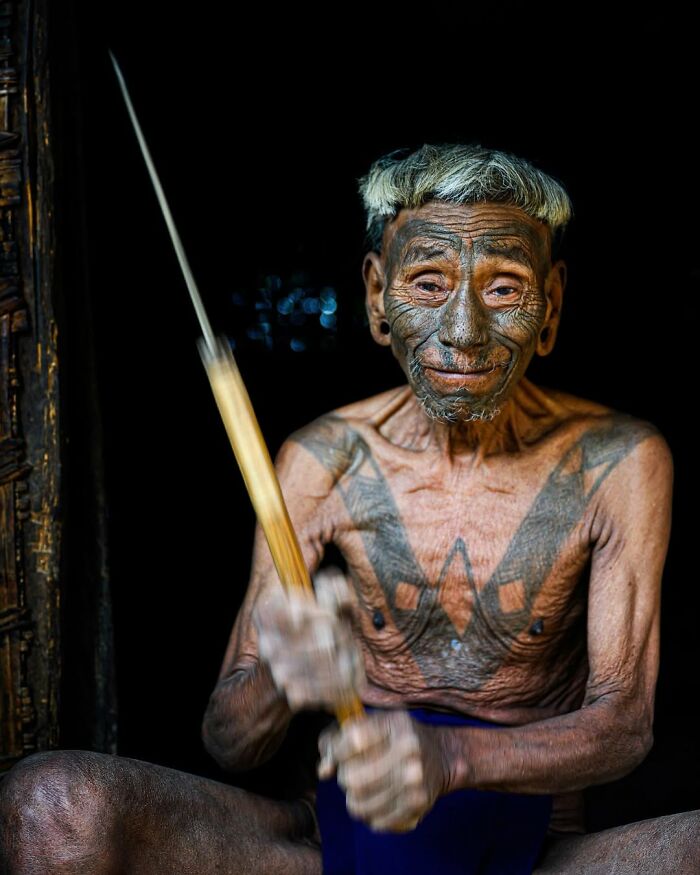 Anciano con tatuajes tradicionales y cabello blanco, retrato elocuente que muestra la cultura de personas mayores globalmente.
