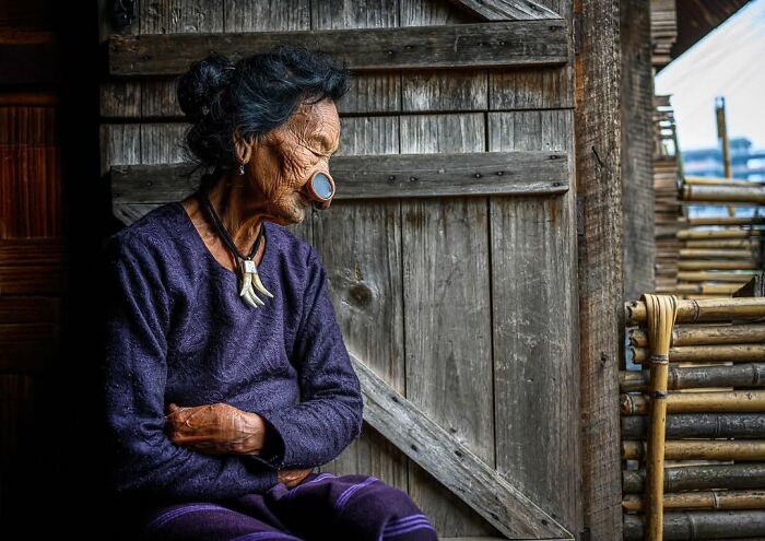 Mujer mayor con nariz decorativa y collar tradicional, retrato elocuente de personas mayores de todo el mundo.