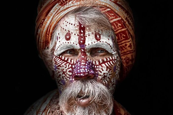 Retrato elocuente de hombre mayor con pintura facial tradicional y turbante, en colección de personas mayores de todo el mundo.