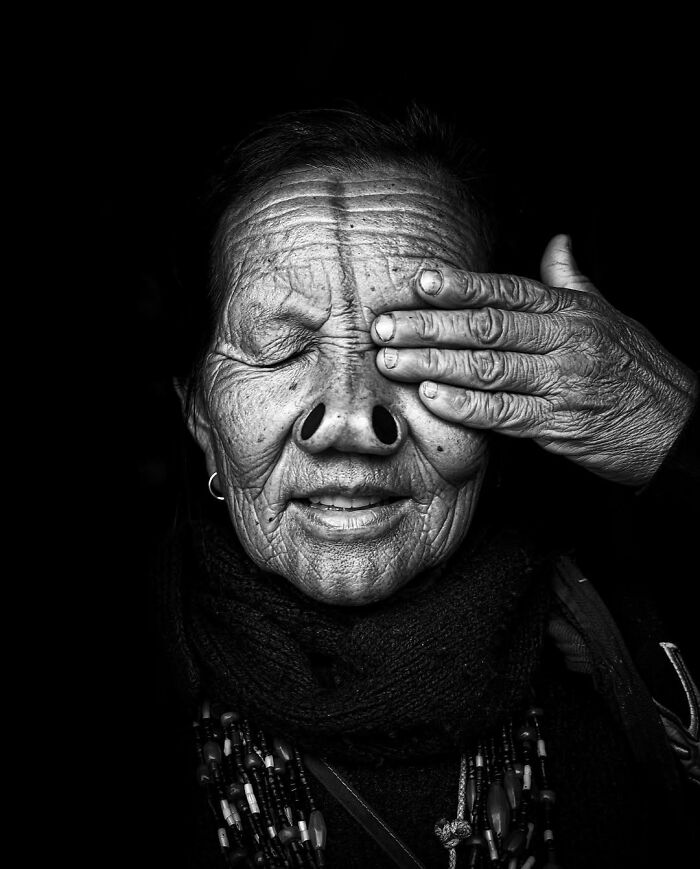 Retrato en blanco y negro de persona mayor con arrugas profundas, mano cubriendo un ojo, de la colección de retratos elocuentes.