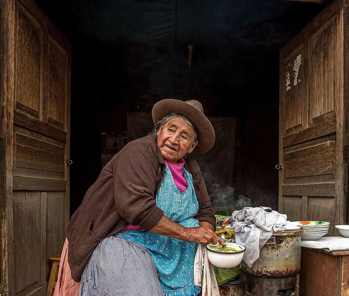 Retrato elocuente de persona mayor en cocina tradicional, mostrando cultura y vida cotidiana en el mundo.