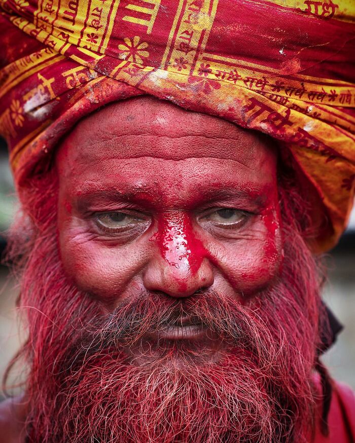 Retrato elocuente de persona mayor con turbante amarillo y rostro pintado de rojo, parte de serie mundial de Massimo Bietti.