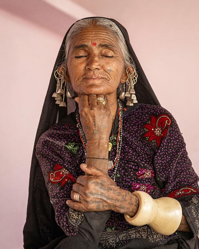 Retrato elocuente de mujer mayor con tatuajes tradicionales y joyería, mostrando la riqueza cultural de personas mayores.