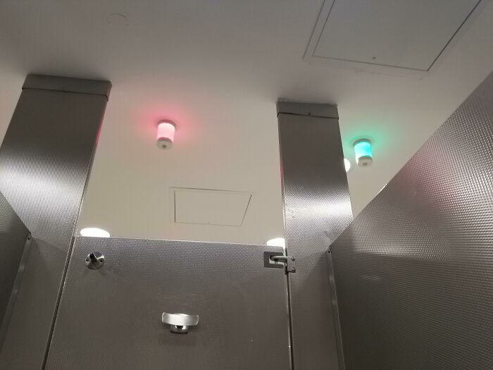 Luz indicadora roja y verde en baño público para señalar la ocupación de cabinas, solución genial a problemas habituales.
