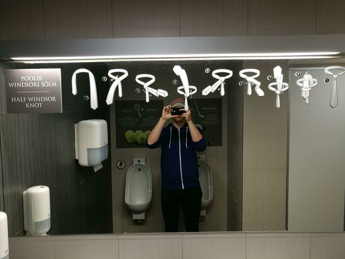 Hombre tomando foto frente a espejo con instrucciones visuales de nudos de corbata para soluciones geniales y problemas habituales.