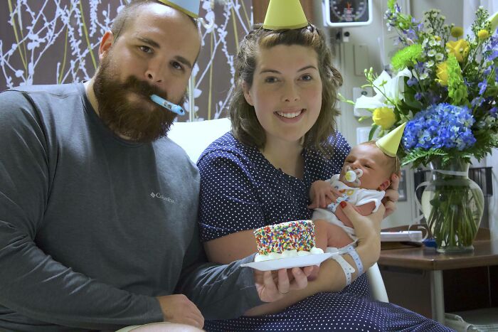 Pareja celebrando cumpleaños con bebé y pastel pequeño, mostrando soluciones geniales a problemas habituales en la vida diaria.
