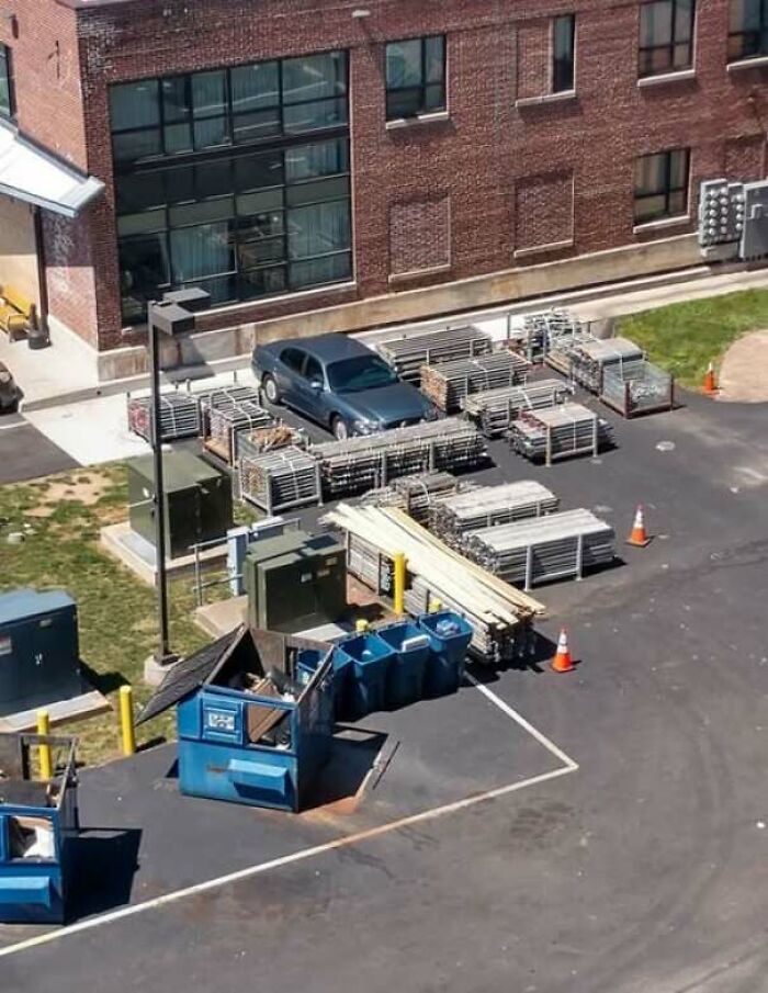 Coche atrapado entre materiales de construcción y estructuras metálicas en un estacionamiento, demostrando cosas que salieron mal.