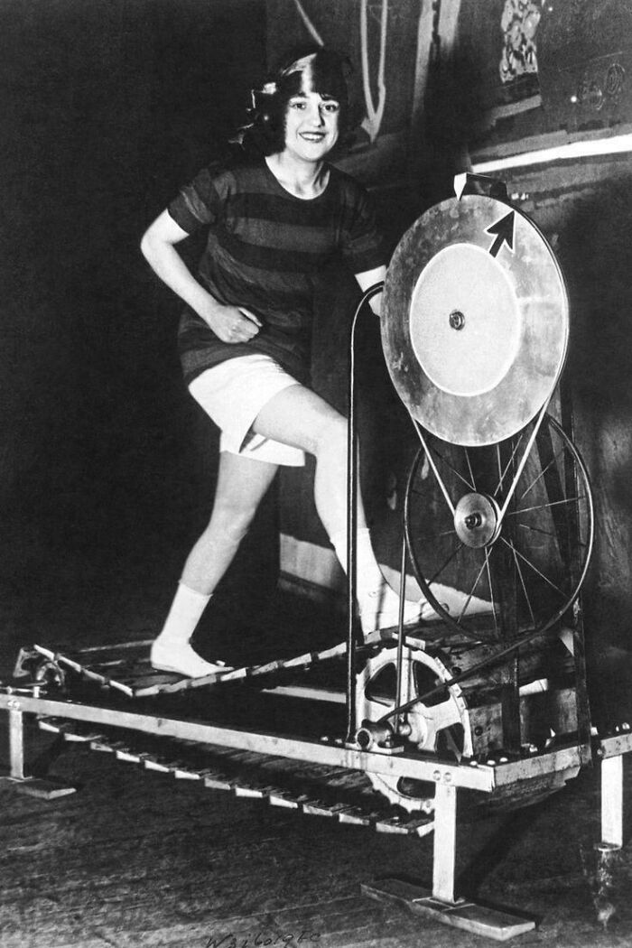 Mujer usando una máquina vintage para ejercicio en cinta caminadora, foto histórica interesante y llamativa.