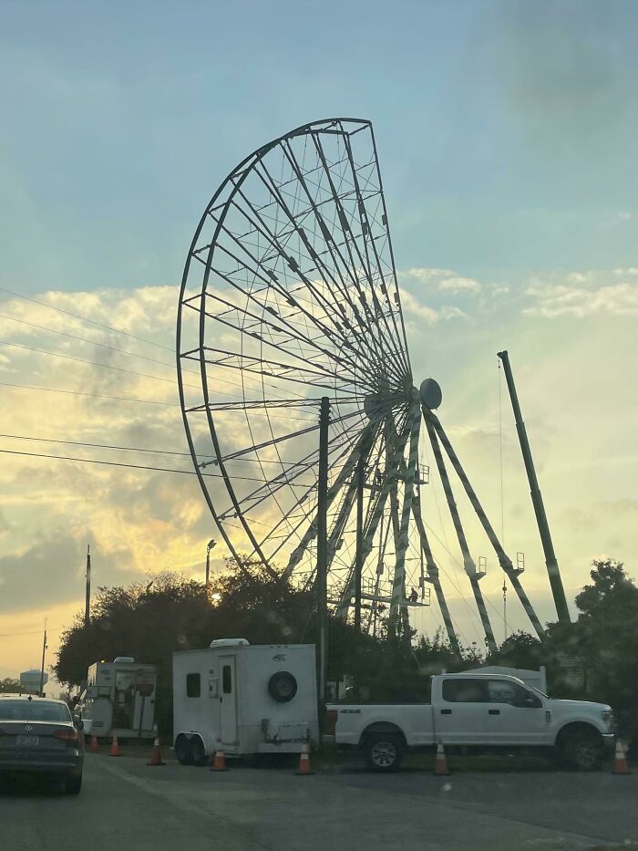 Rueda de la fortuna sin cabinas al atardecer con camiones y grúas en construcción, fotos interesantes.
