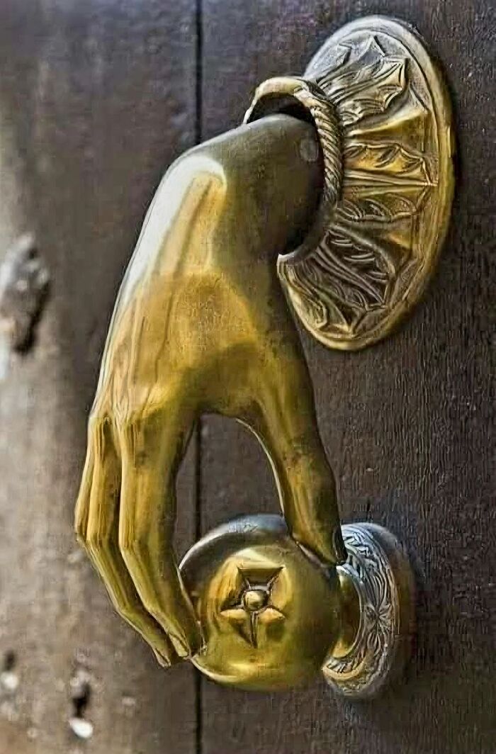 Manija de puerta en forma de mano de metal, detalle curioso en casas olvidadas o abandonadas.