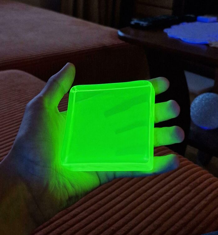 Mano sosteniendo un objeto cuadrado que emite luz verde brillante en un entorno oscuro, foto interesante para SEO.