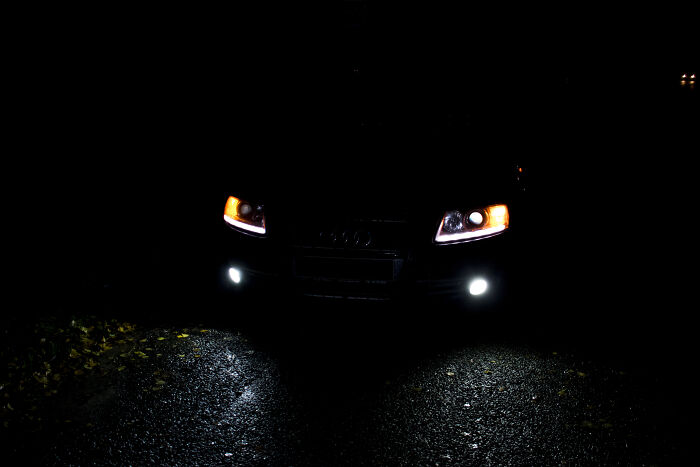 Faros delanteros encendidos de coche en la oscuridad, un objeto interesante que parece otras cosas por la iluminación.