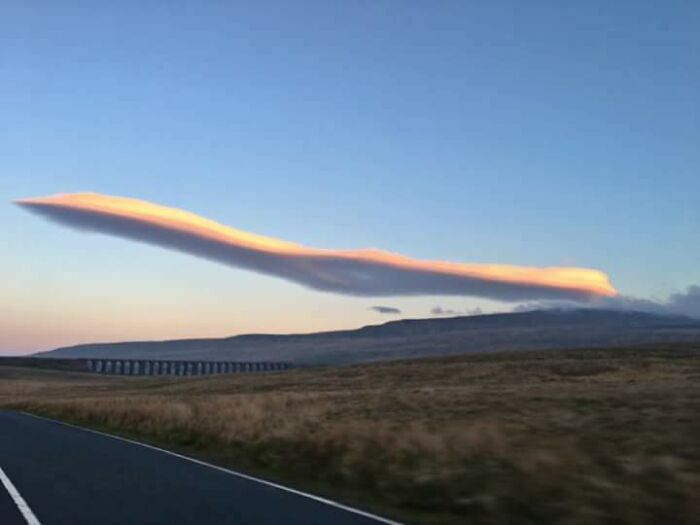 Nube curiosa y alargada en el cielo que parece un objeto interesante en un paisaje abierto al atardecer.