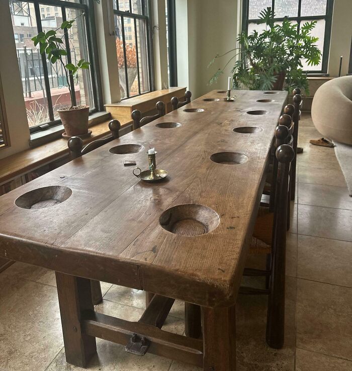Mesa de madera antigua con agujeros cuadrados para tazas, mostrando una comparación increíble desde una perspectiva temporal.