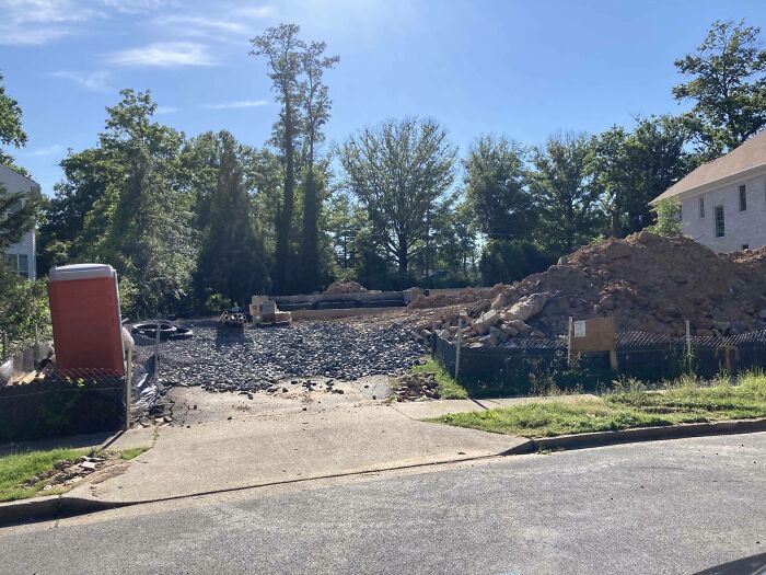 Terreno en construcción con escombros y porta sanitario, reflejando un día peor para padres y madres cuidando la obra.