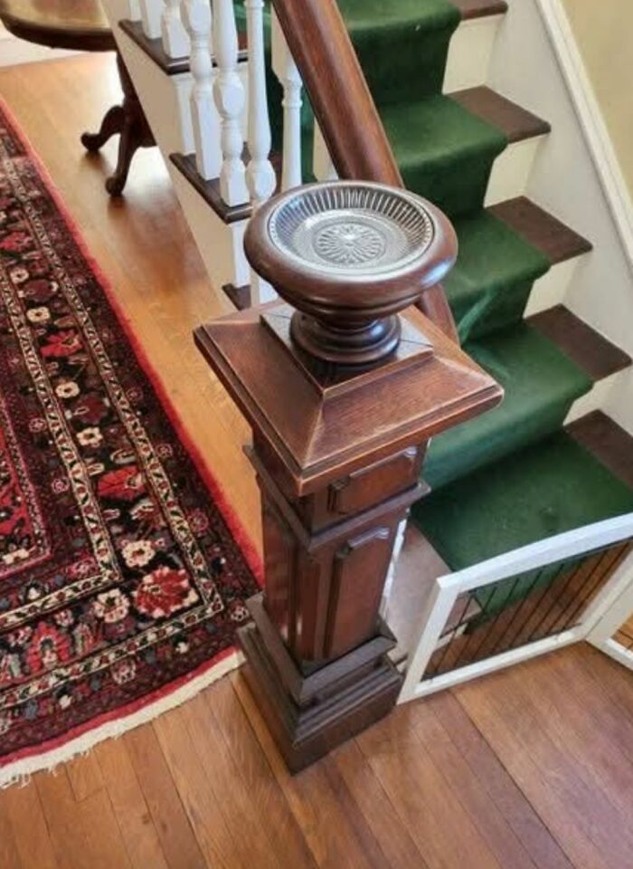 Detalle de barandal de madera antigua en casa con alfombra y escalera verde, ejemplo de descubrimientos curiosos en casas olvidadas.