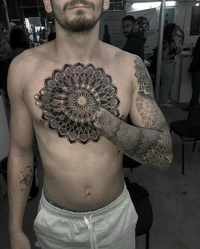 Hombre con tatuajes geométricos y mandalas en pecho y brazo, ejemplo de personas que decidieron hacerse tatuajes.