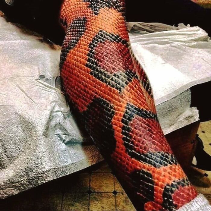 Tatuaje tridimensional en pierna con diseño de escamas que simula piel de serpiente, ejemplo destacado del arte corporal.