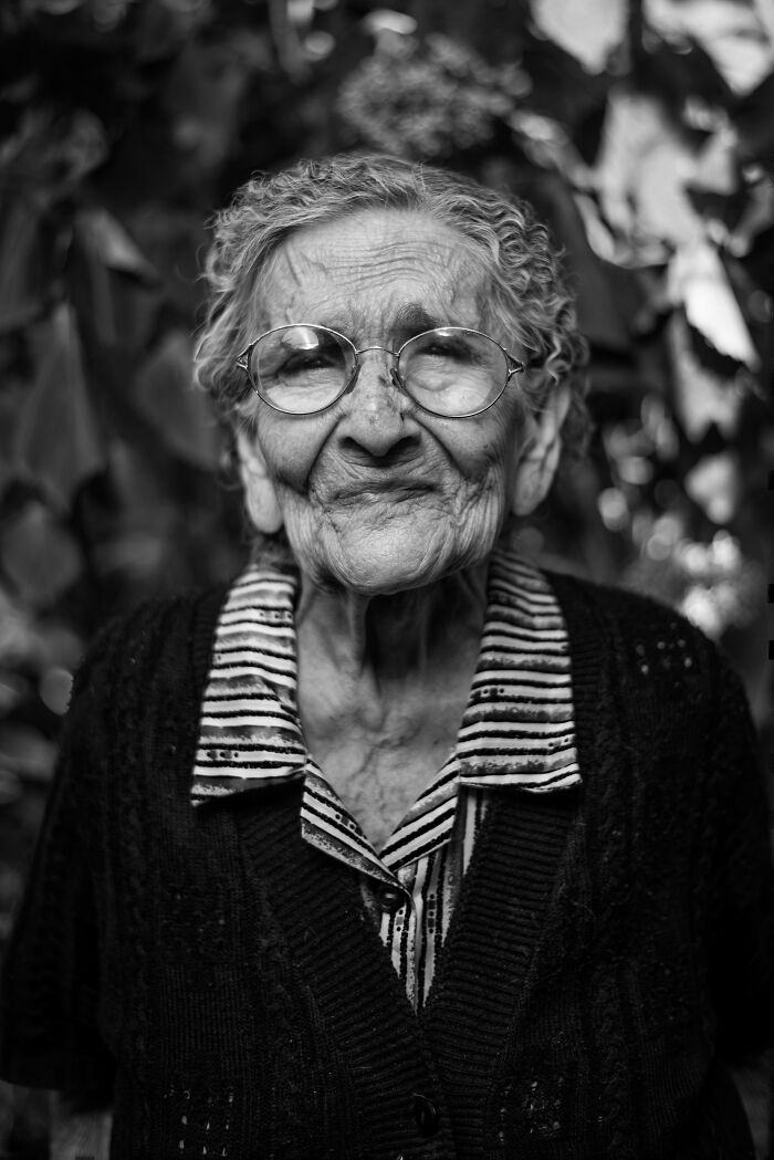 Mujer mayor con gafas, cabello canoso y expresión amable, mostrando rasgos únicos y lotería genética en blanco y negro.