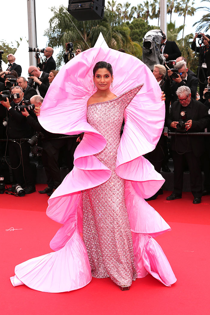 Mujer con vestido rosa voluminoso y lentejuelas en la alfombra roja, entre fotógrafos, desastres de moda Festival de Cannes 2025.