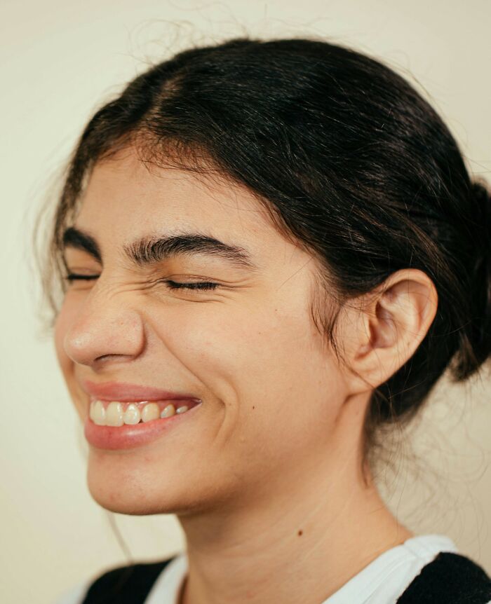 Joven sonriente con expresión feliz, reflejando genes buenos o malos en apariencia natural y cabello oscuro recogido.
