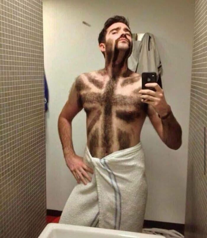 Hombre posando con un corte de vello corporal creativo y un toallero blanco en un baño, momentos únicos capturados en foto.