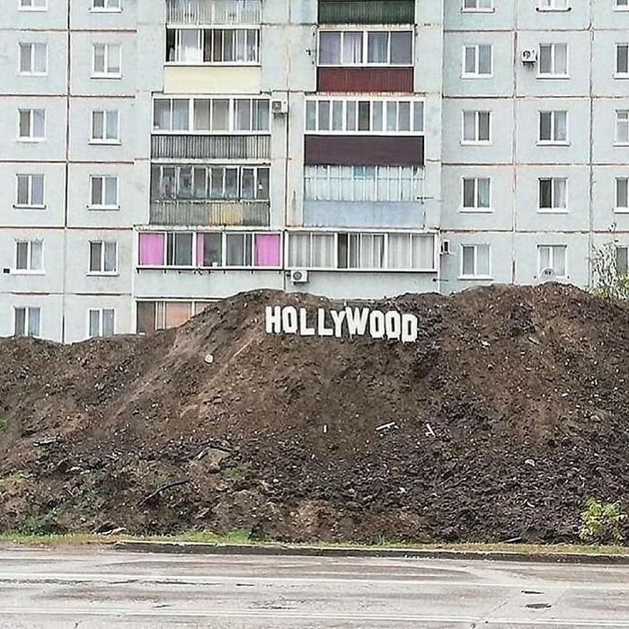 Montículo de tierra con letras que imitan el cartel de Hollywood frente a un edificio de apartamentos, imagen sorprendente y curiosa.