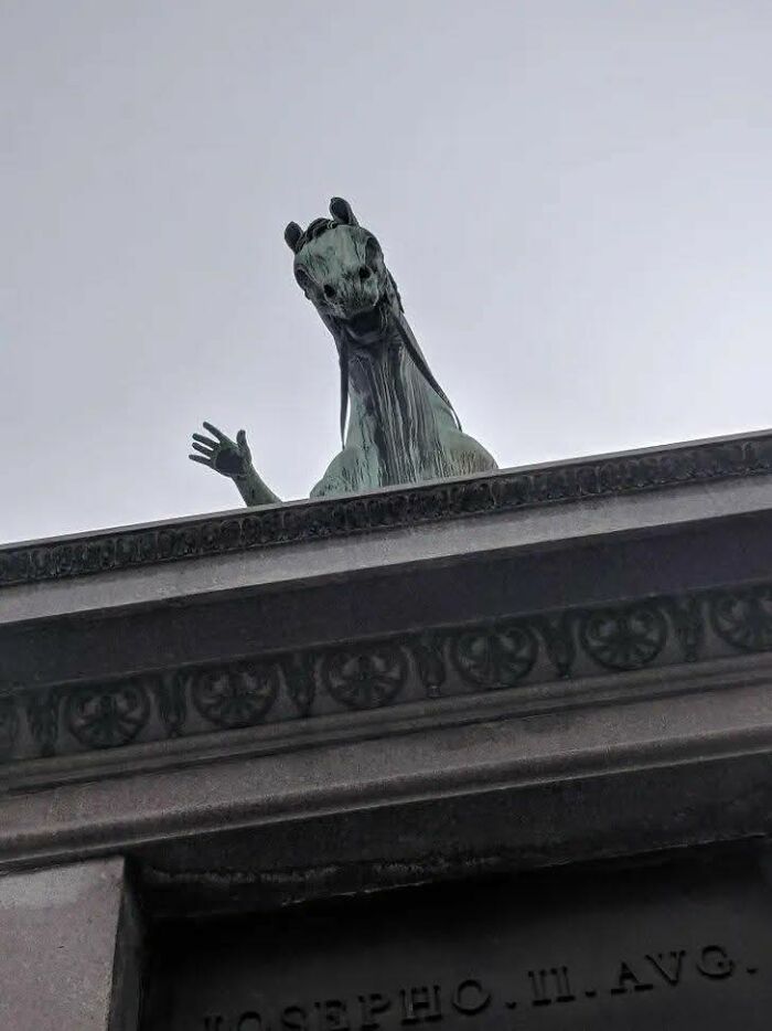 Estatua de caballo saludando desde la cima de un edificio en foto que captura momento único e inesperado.