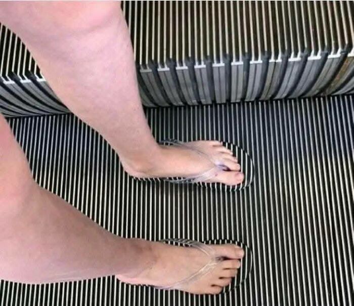 Persona en escalera mecánica con zapatos transparentes que crean un efecto visual confuso, imagen para personas que menos mal hicieron foto.