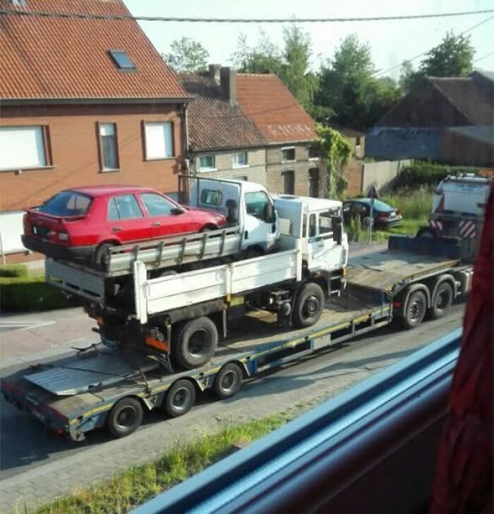 Camión cargado con otro camión y un coche rojo sobre este, una imagen que nadie habría creído sin foto.