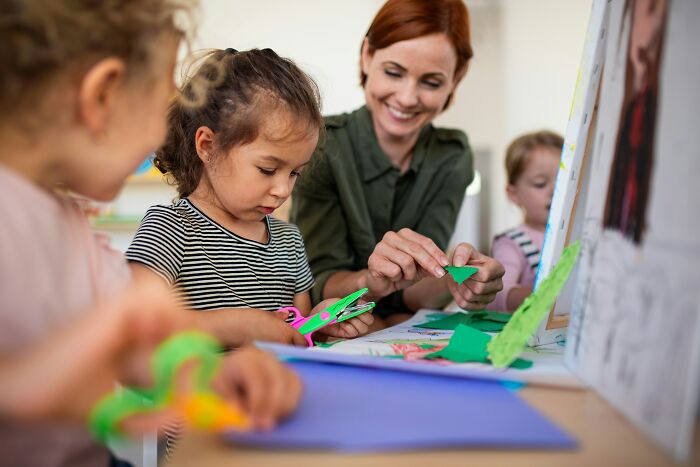 Niñas y maestra realizando manualidades, destacando la creatividad y la lotería genética en personas bastante únicas.