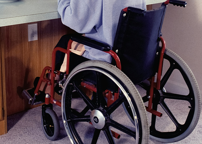 Persona en silla de ruedas recibiendo consejos vitales del personal sanitario y de emergencias para su cuidado.