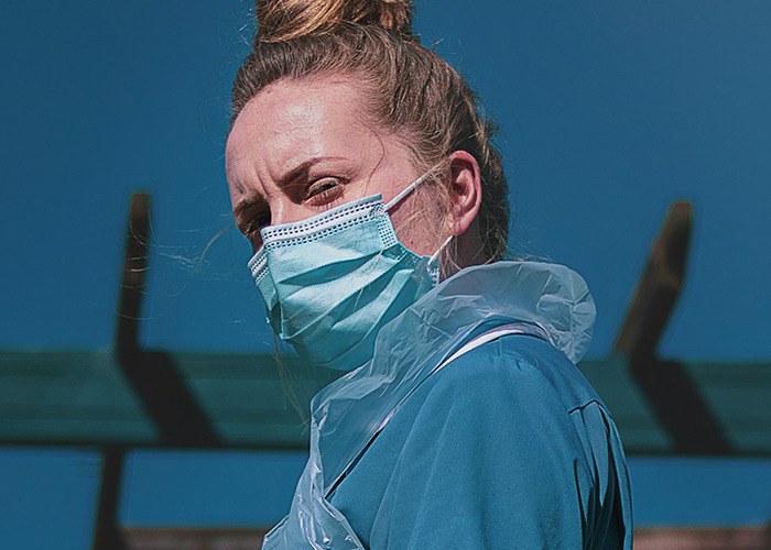 Personal sanitario con mascarilla y bata azul ilustrando consejos vitales de emergencias médicas en ambiente exterior.