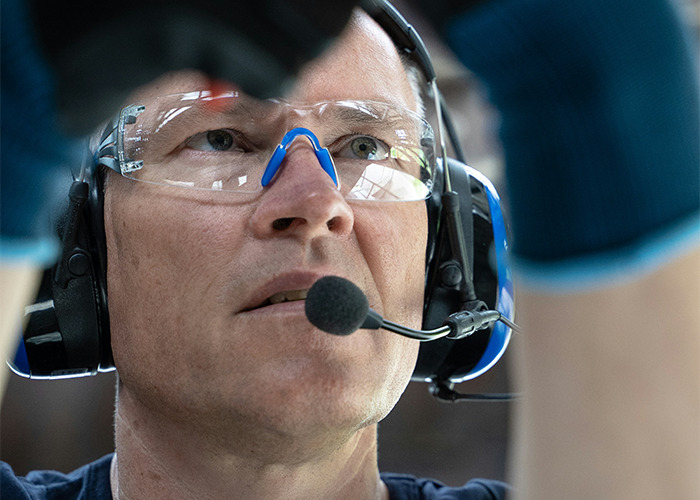 Hombre del personal sanitario con gafas de protección y auriculares comunicándose en un entorno de emergencias.