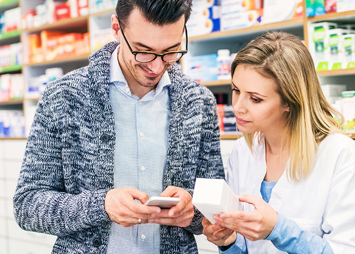 Personal sanitario asesorando a un paciente sobre medicamentos en farmacia, ofreciendo consejos vitales para emergencias.