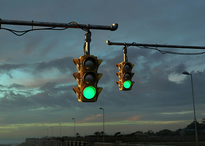 Semáforo en verde al atardecer con consejos vitales del personal sanitario y de emergencias para seguridad vial.