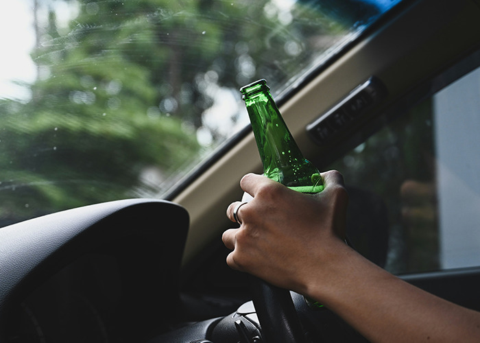 Conductor sujetando una botella verde dentro del coche, ilustrando consejos vitales del personal sanitario y de emergencias.