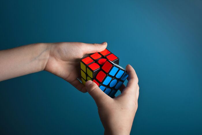 Manos manipulando un cubo de Rubik, representando personas únicas y la complejidad de la lotería genética.