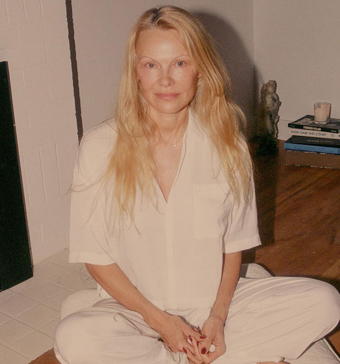 Pamela Anderson con look natural sentada en interiores antes de su regreso al estilo glamuroso de los 90