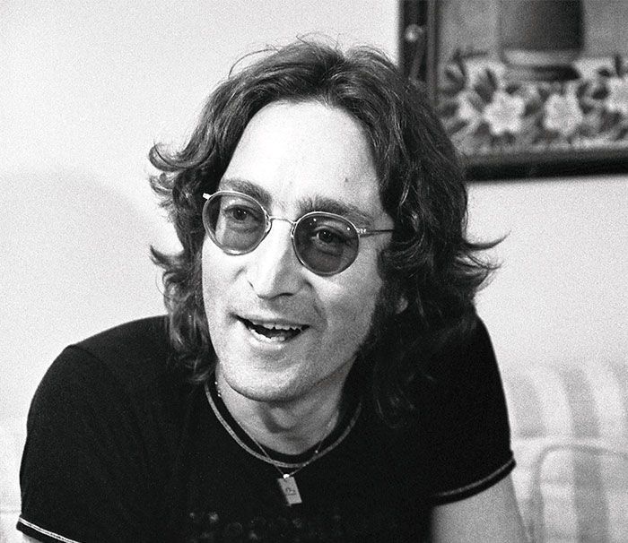 Hombre con gafas de sol y cabello rizado sonriente, representación de celebridades problemáticas conocidas.
